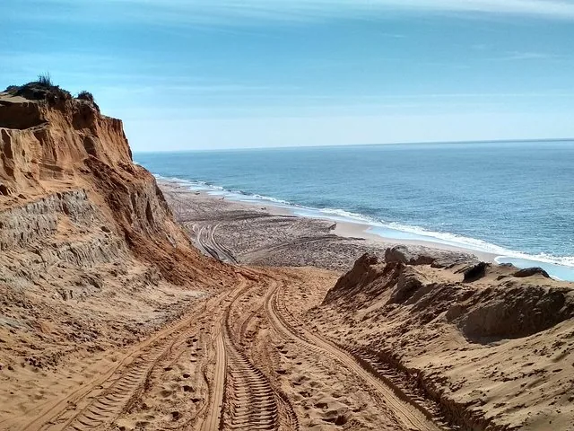 Sandiger Weg, der zu einem Strand mit steilen Klippen hinunterführt