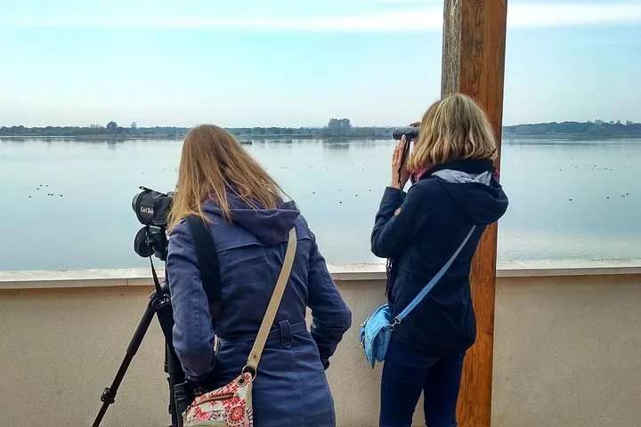 Two women observing wildlife through a spotting scope and binoculars